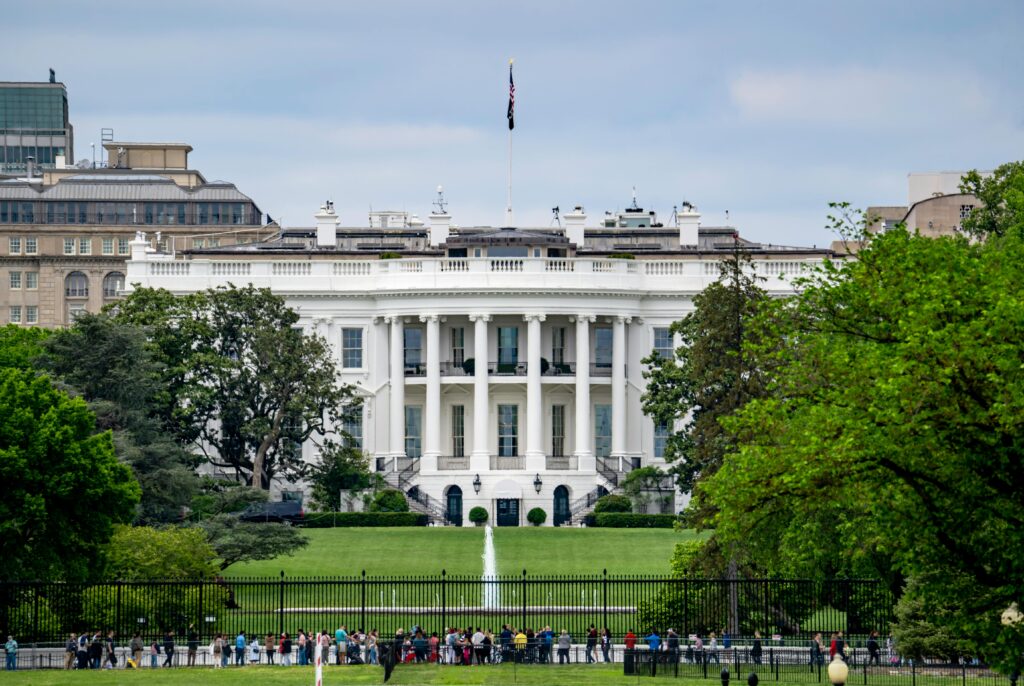 A scenic view of The White House, a renowned landmark in Washington, DC, surrounded by greenery and tourists.