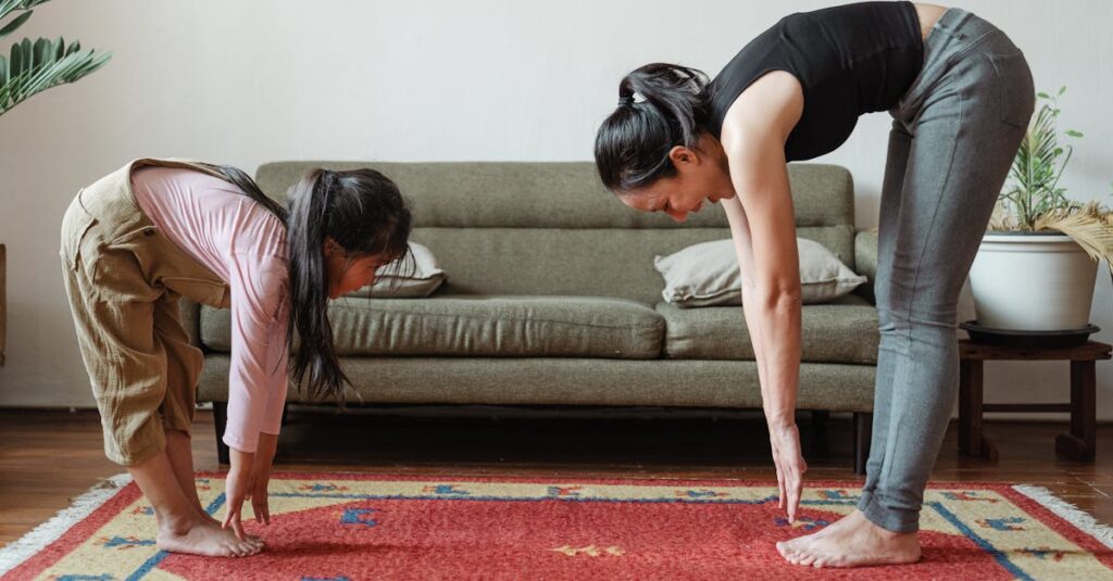 Side view of flexible young ethnic mother exercising with cute daughter while standing against each other on floor carpet near cozy sofa in modern living room in morning